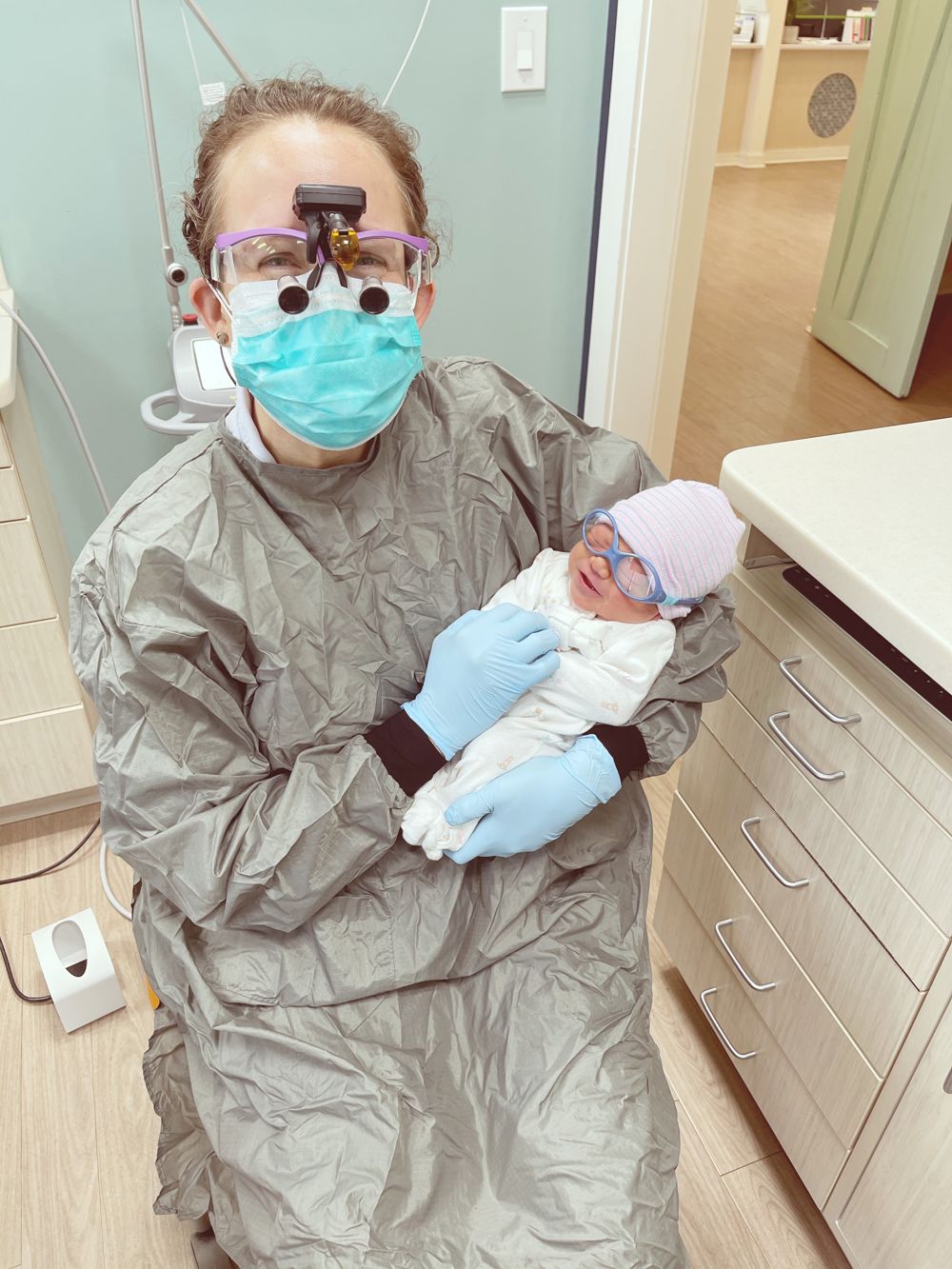 Dr. Bracy holding a newborn in the La Petite Dent office