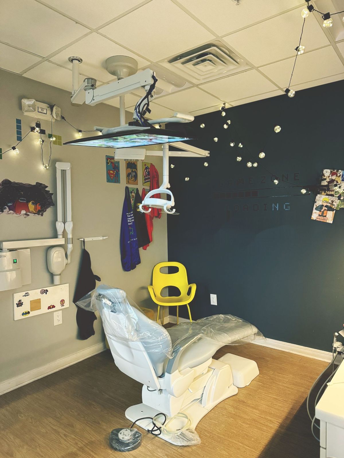 A treatment room with string lights, superhero posters, and a Game Zone wall